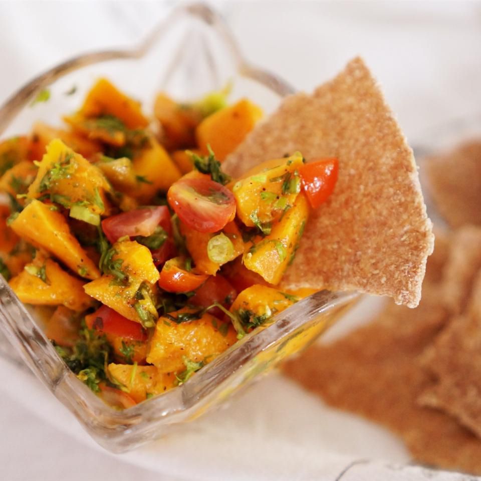 close up view of Mango Salsa in a glass bowl with a tortilla chip