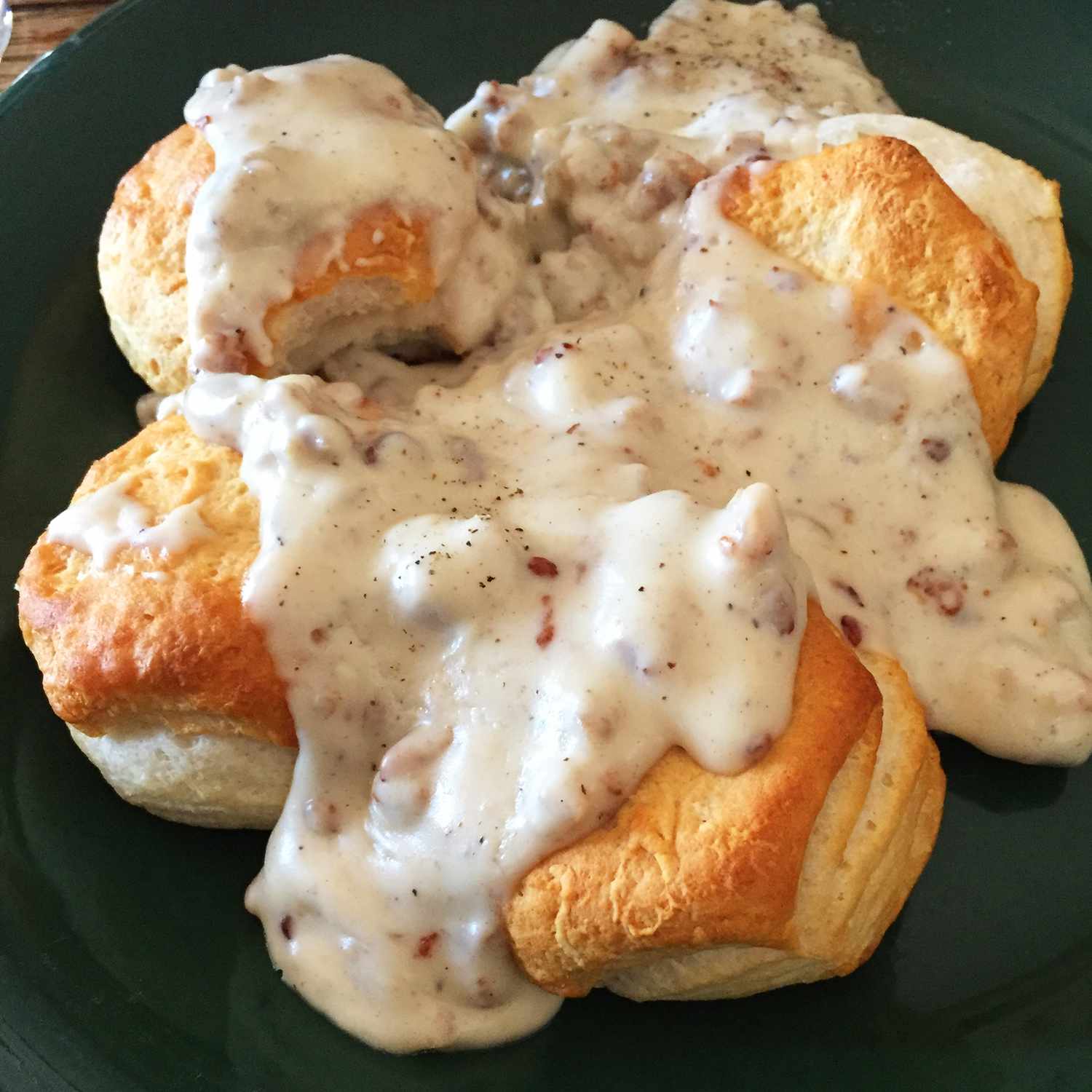 close up view of Bill's Sausage Gravy over biscuits on a green plate