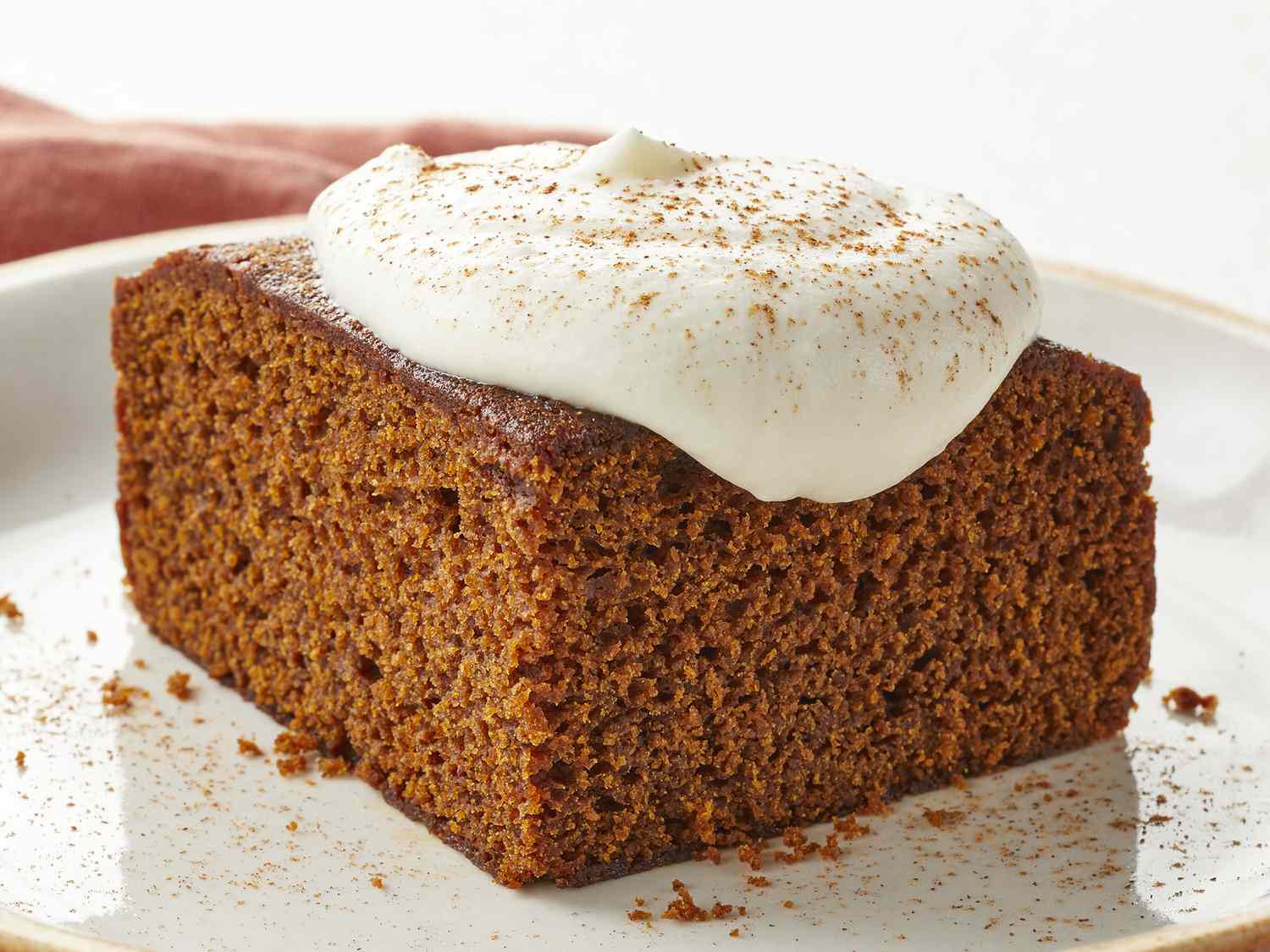 low angle looking at a slice of gingerbread topped with whipped cream