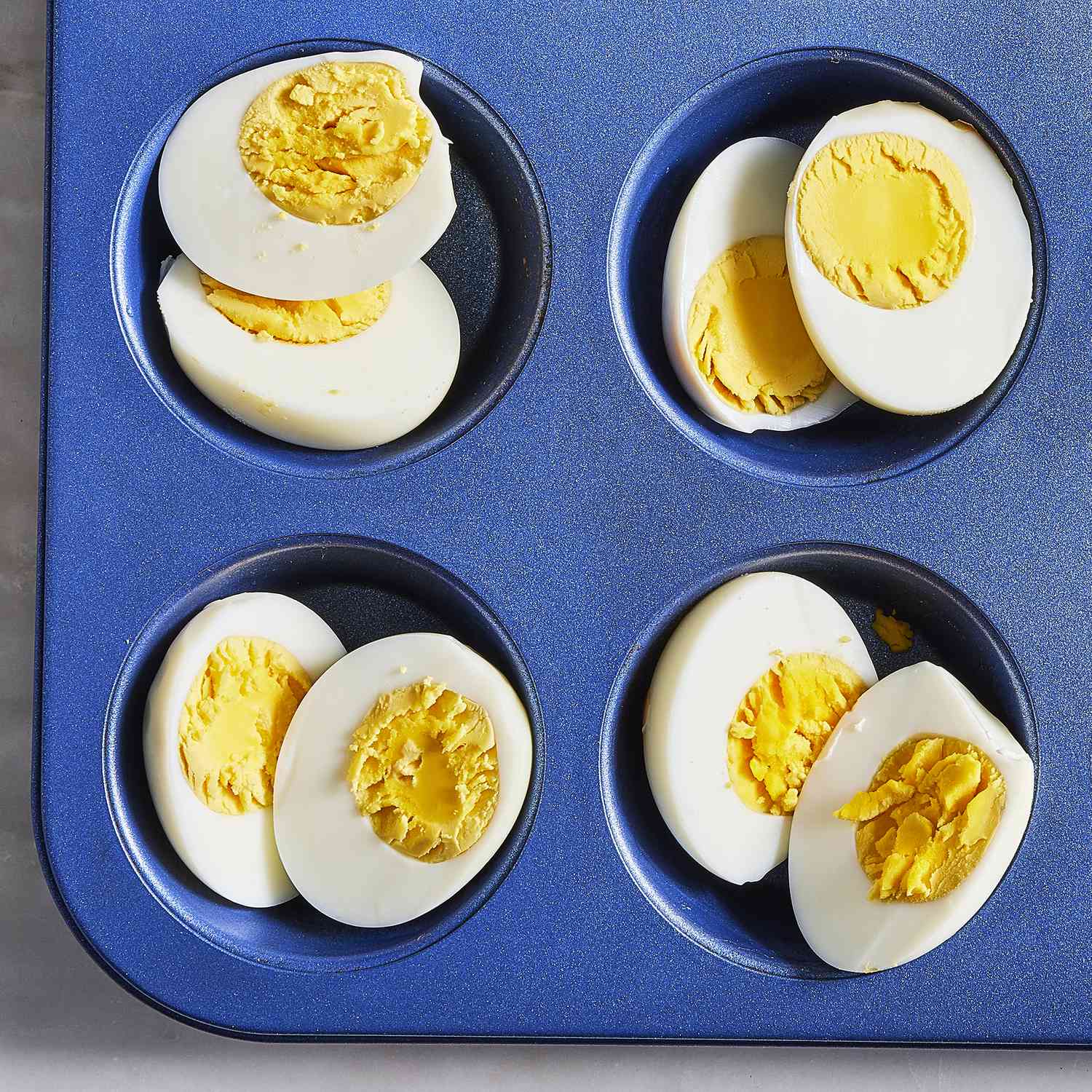 overhead view of hard boiled eggs cut in half in a muffin tin