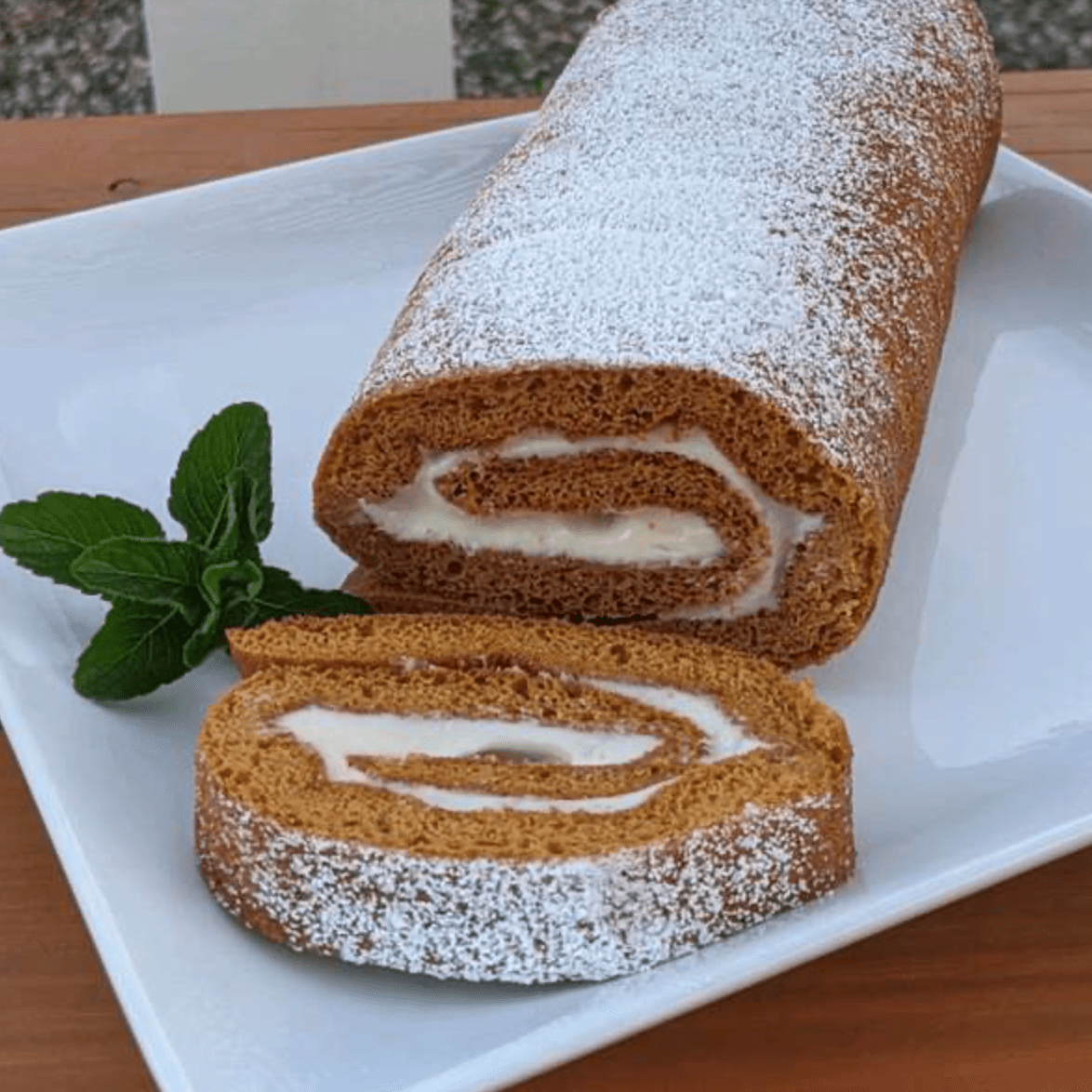 pumpkin roll on square white plate with mint garnish