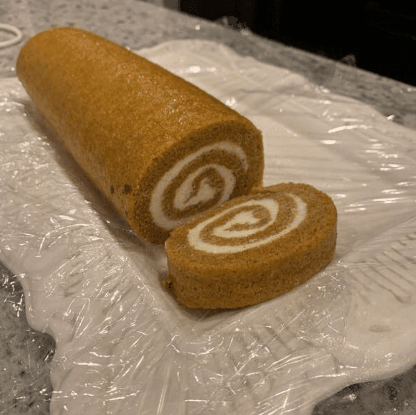 pumpkin roll on white serving plate on storage wrap
