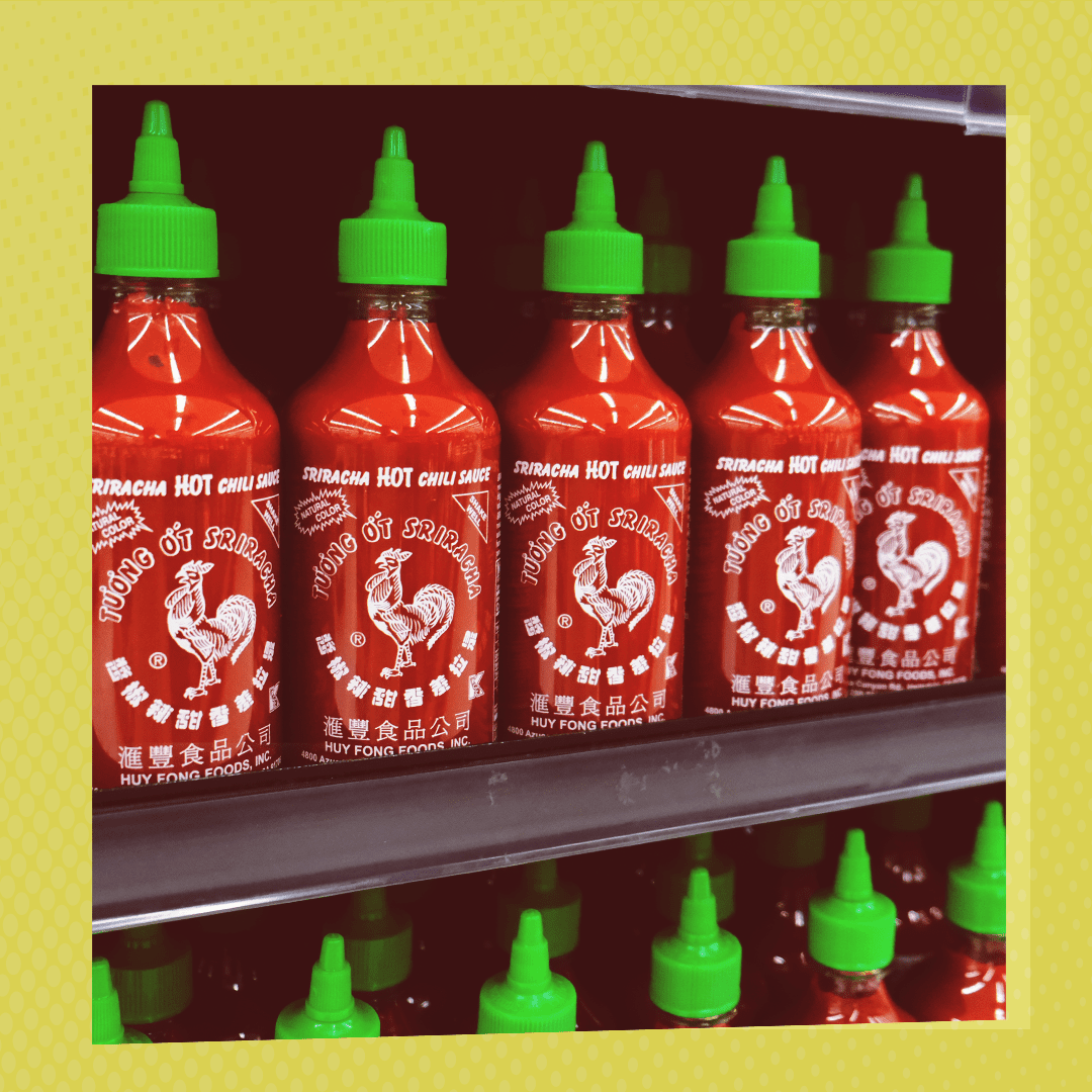 A grocery store shelf full of Huy Fong Food sriracha sauce bottles.