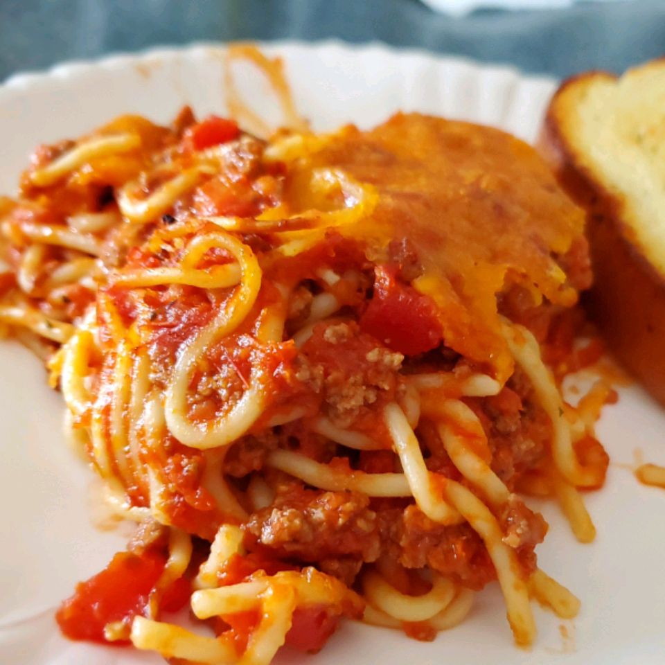 close up view of Basic Baked Spaghetti on a white plate with a slice of toast on the side