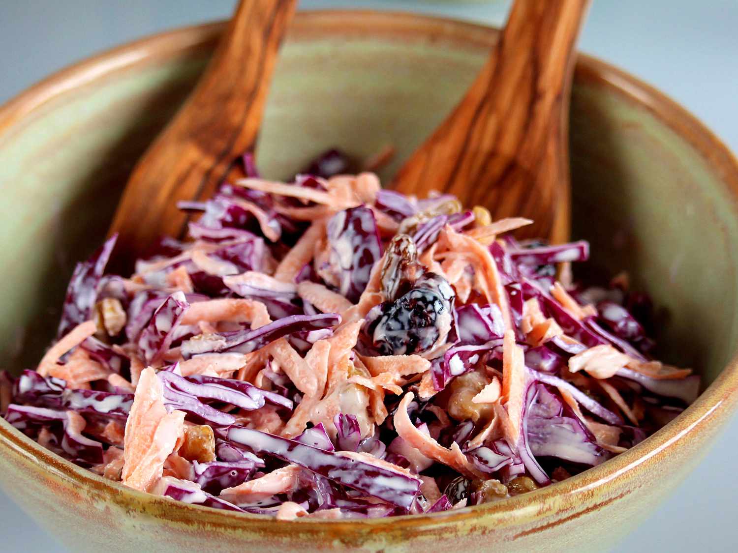 close up view of Red Cabbage Slaw in bowl with wooden serving spoons