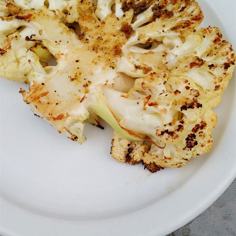 close up view of a Grilled Cauliflower steak on a white plate