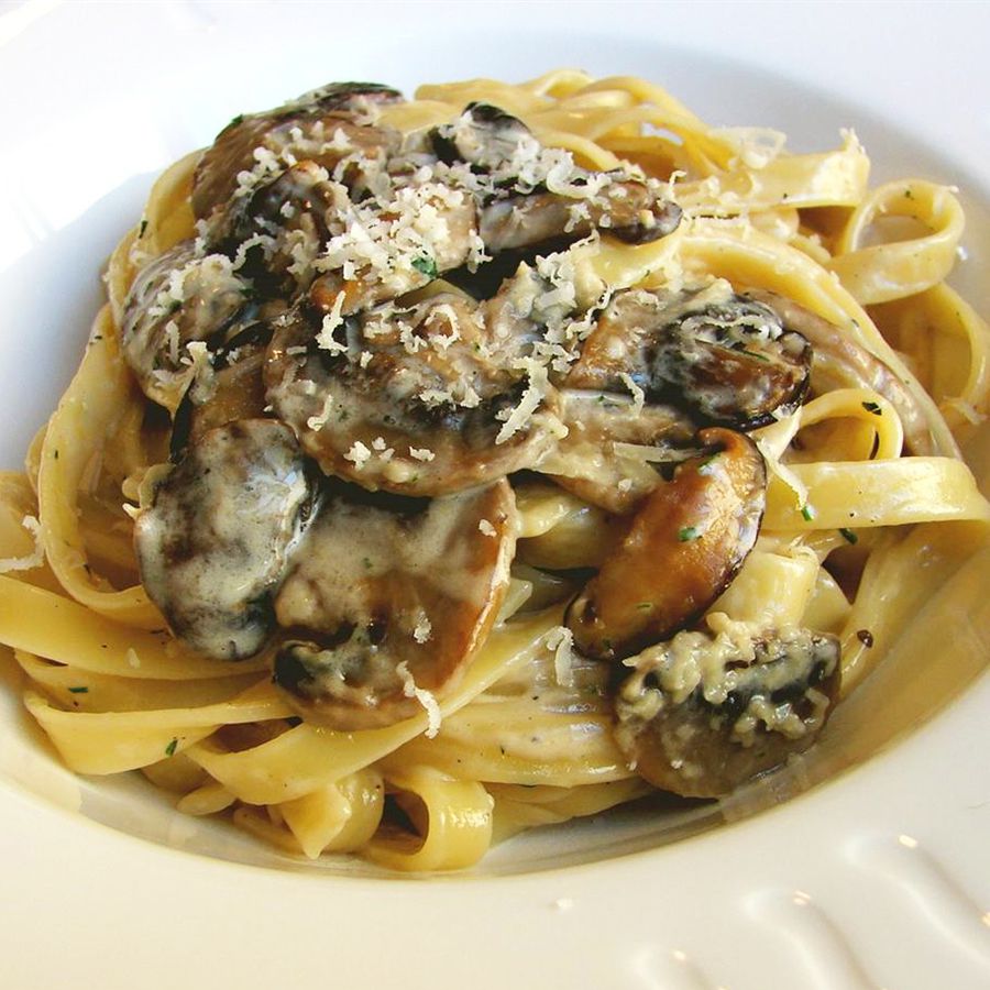 close up view of Chef John's Creamy Mushroom Pasta garnished with cheese in a white bowl