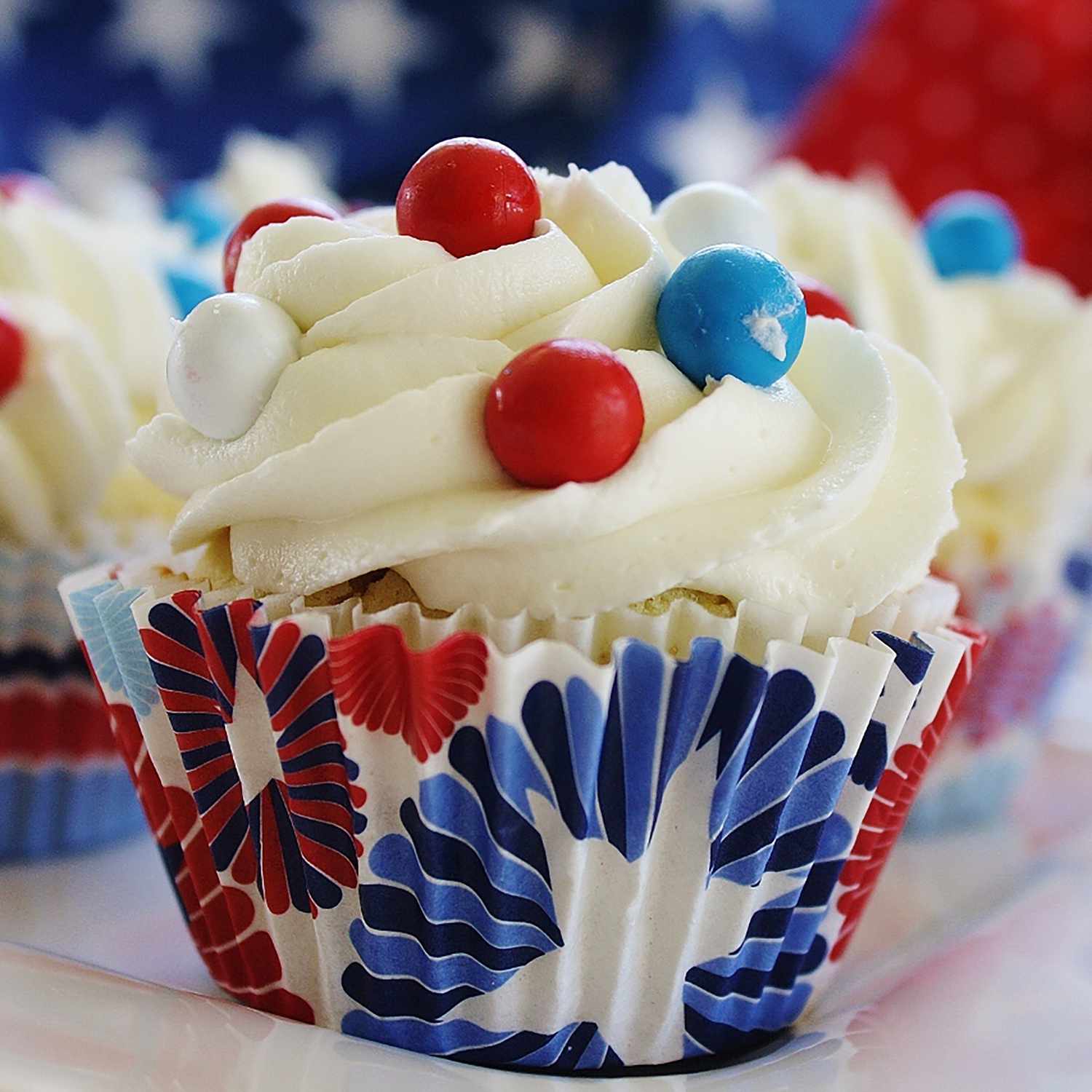 Close up of a white frosted cupcake decorated with red and blue candies for the 4th of July