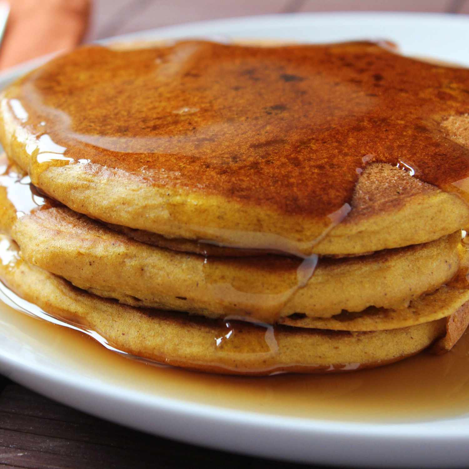 closeup of three golden-brown pancakes covered with maple syrup