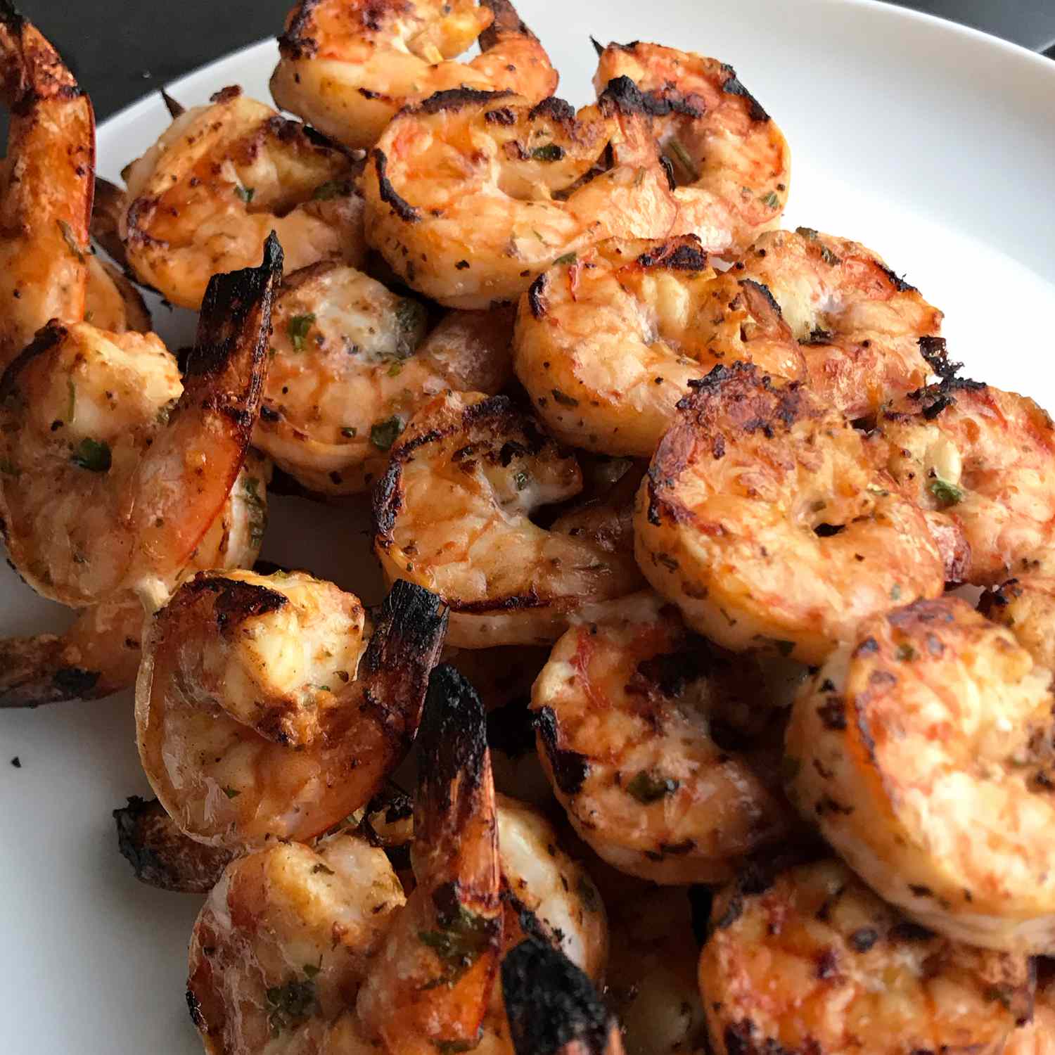 close up view of Grilled Marinated Shrimp on skewers on a white platter