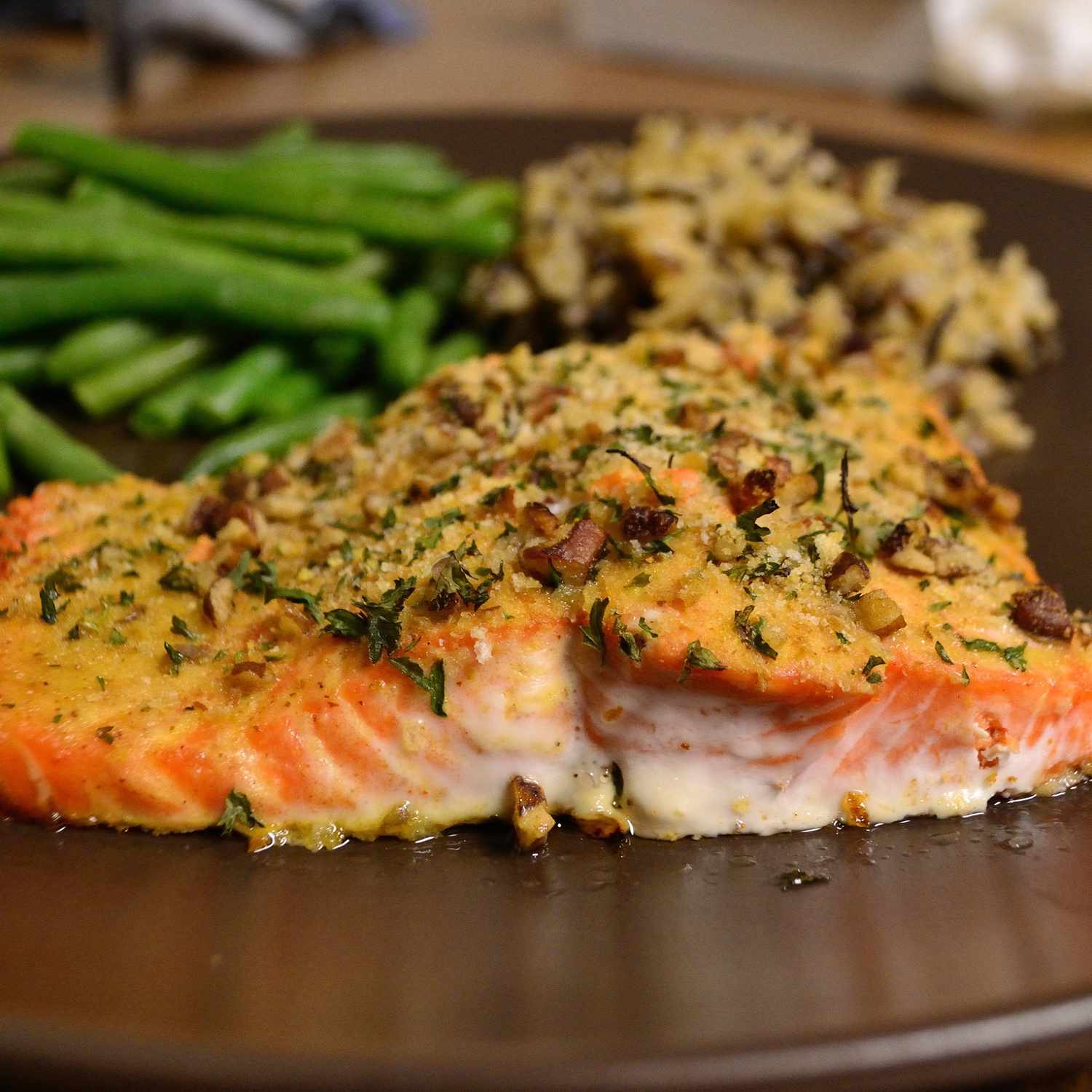 close up view of a Baked Dijon Salmon fillet with wild rice and green bean on a plate