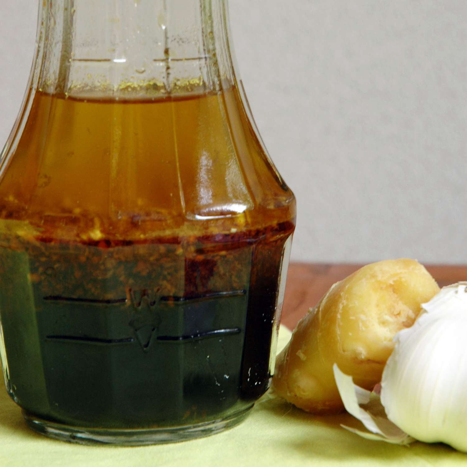 close up view of Asian Ginger Dressing in a bottle, next to ginger and garlic