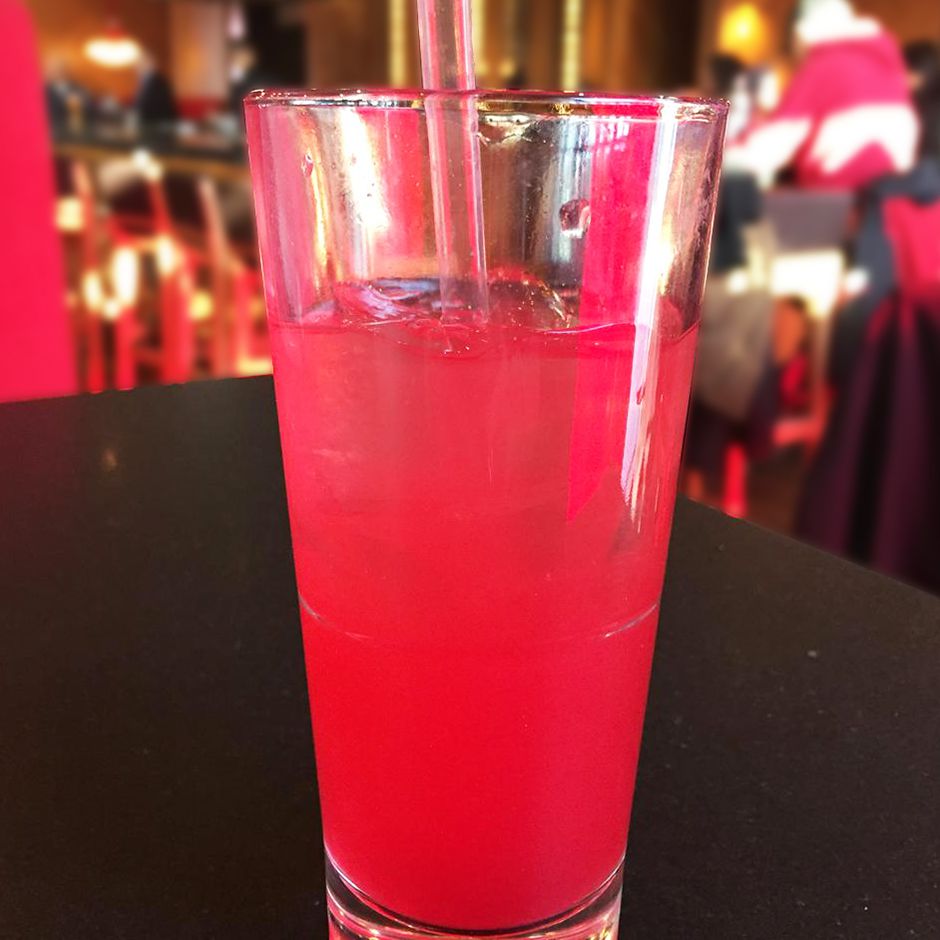 close up view of a Singapore Sling Cocktail, a pink cocktail in a glass with a straw