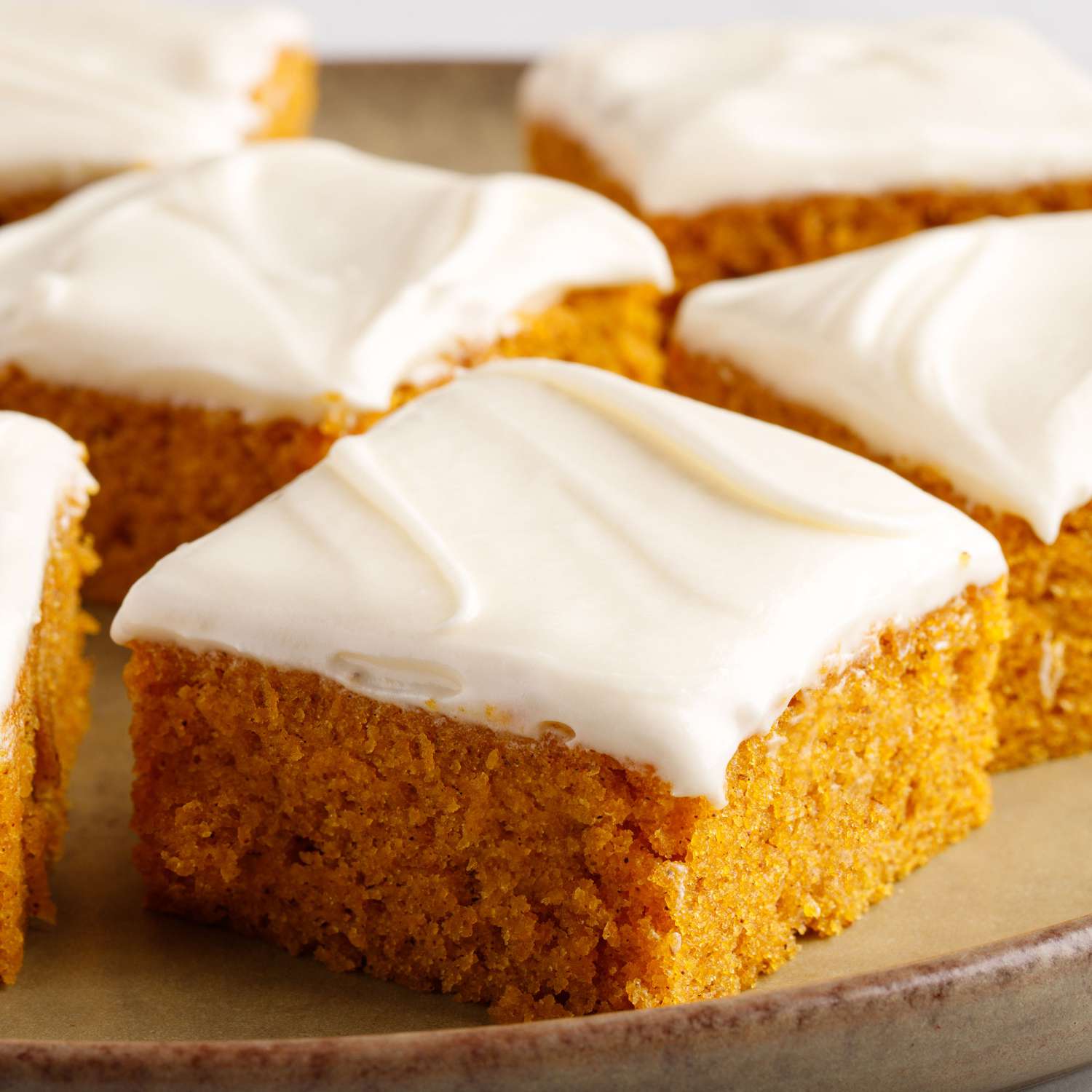 a low angle super close up view of several frosted pumpkin bars sliced and plated