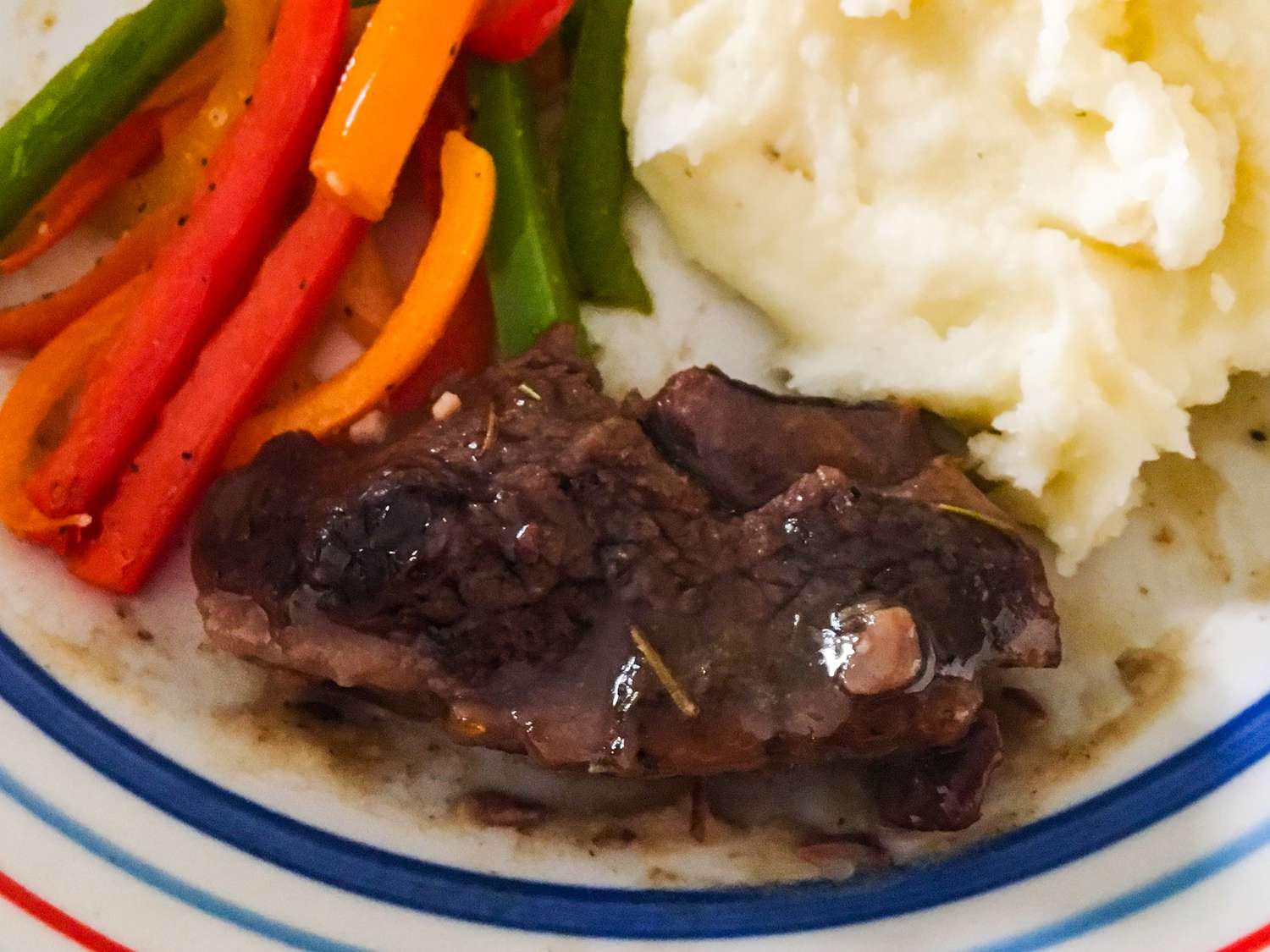 close up view of a lamb chop served with mashed potatoes and peppers