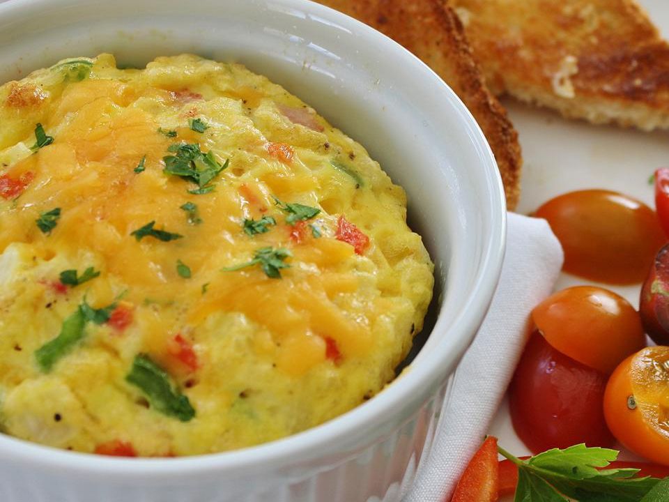 close up view of an Oven Baked Omelet in a white ramekin with toast and tomatoes on the side