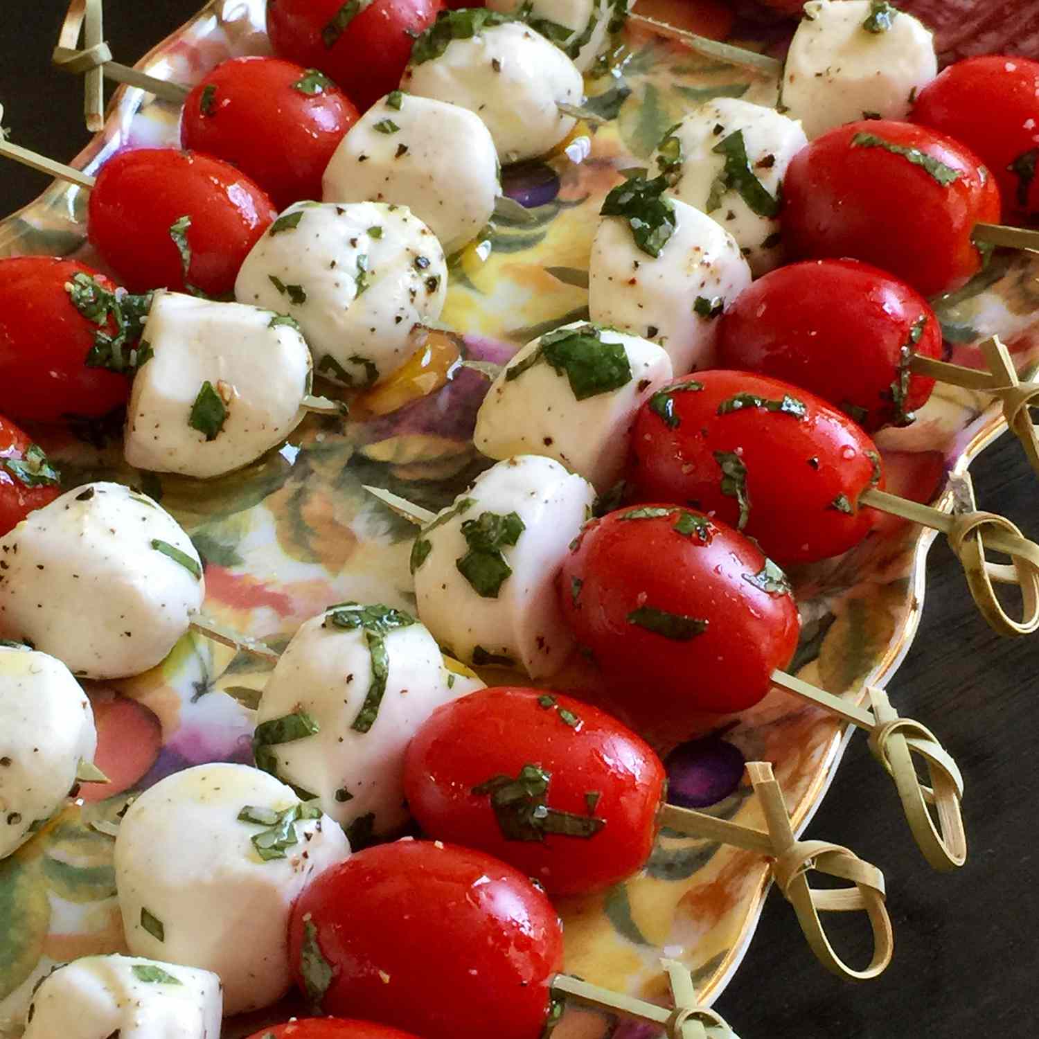 close up view of mozzarella balls and cherry tomatoes with fresh basil on sticks