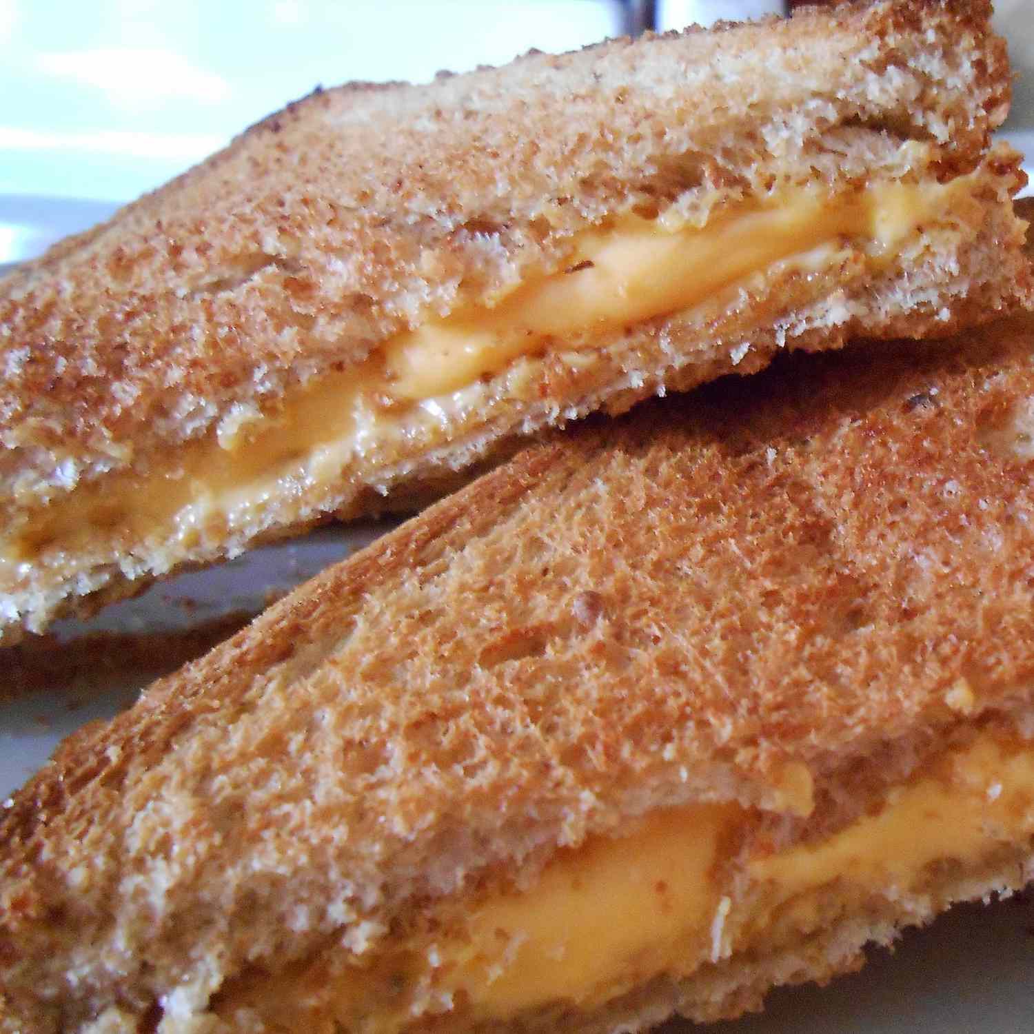 close up view of a Grilled Cheese Sandwich sliced in half, on a plate