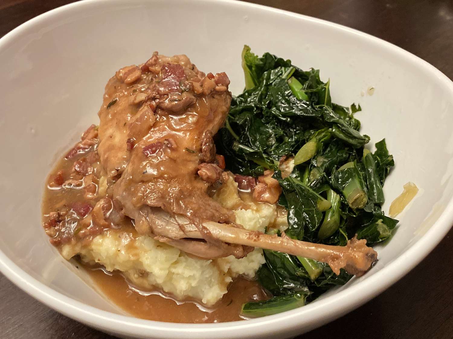 close up view of Hasenpfeffer (Rabbit Stew) served with mashed potatoes and greens in a bowl