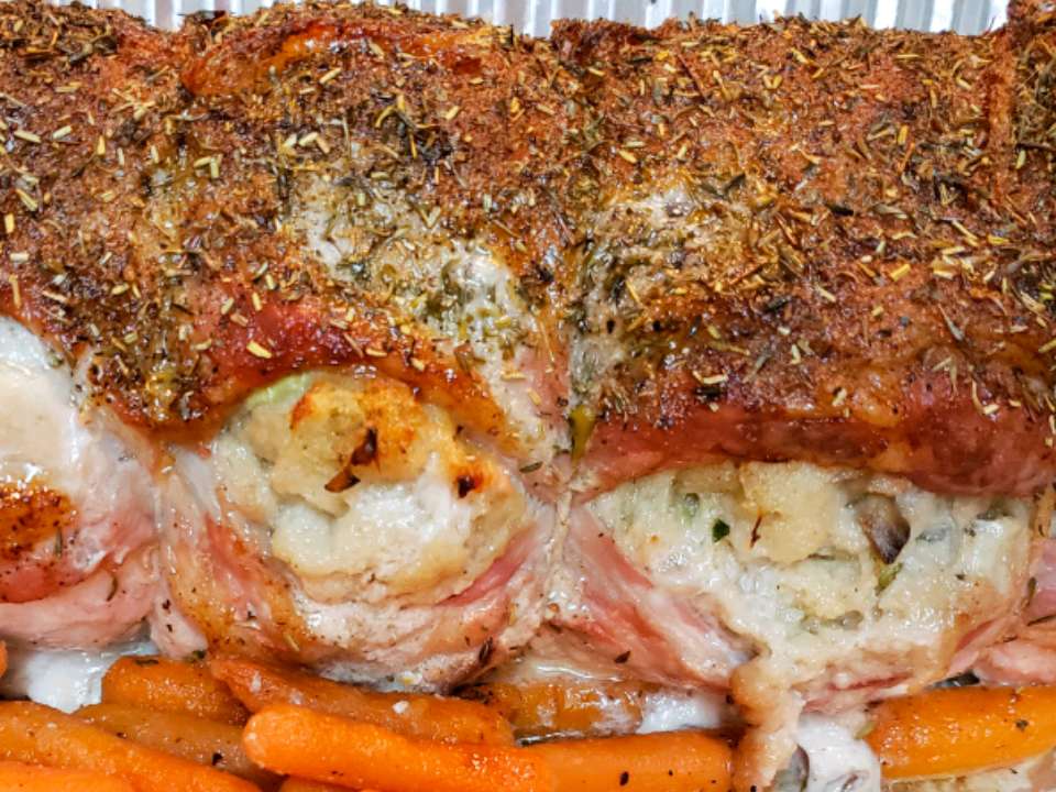 close up view of Stuffed Pork Loin with carrots in a baking dish