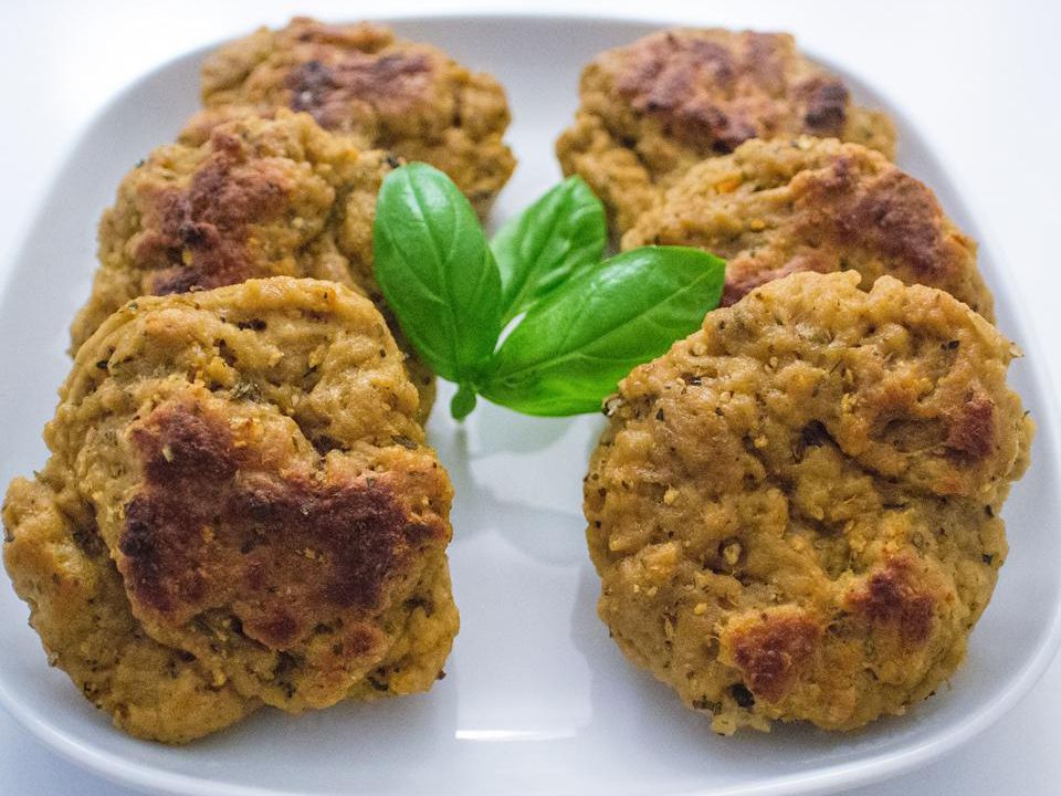 close up view of seitan patties garnished with fresh basil, on a white platter