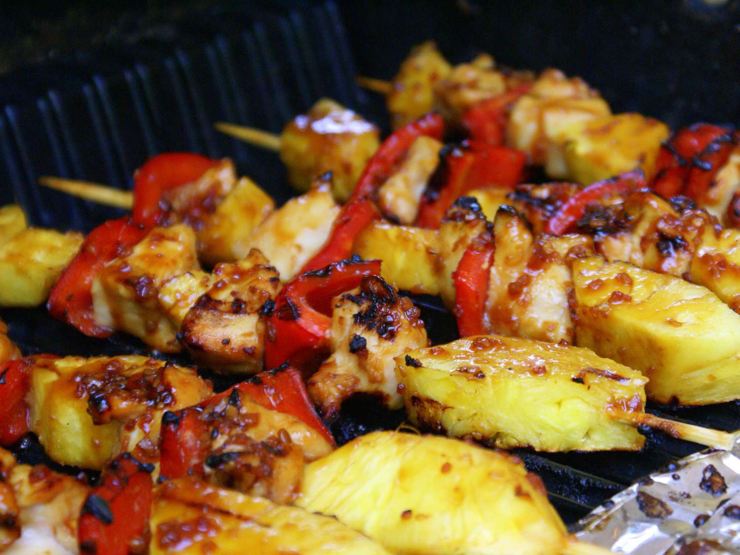 close up view of Chicken Kabobs with peppers and pineapple on a grill