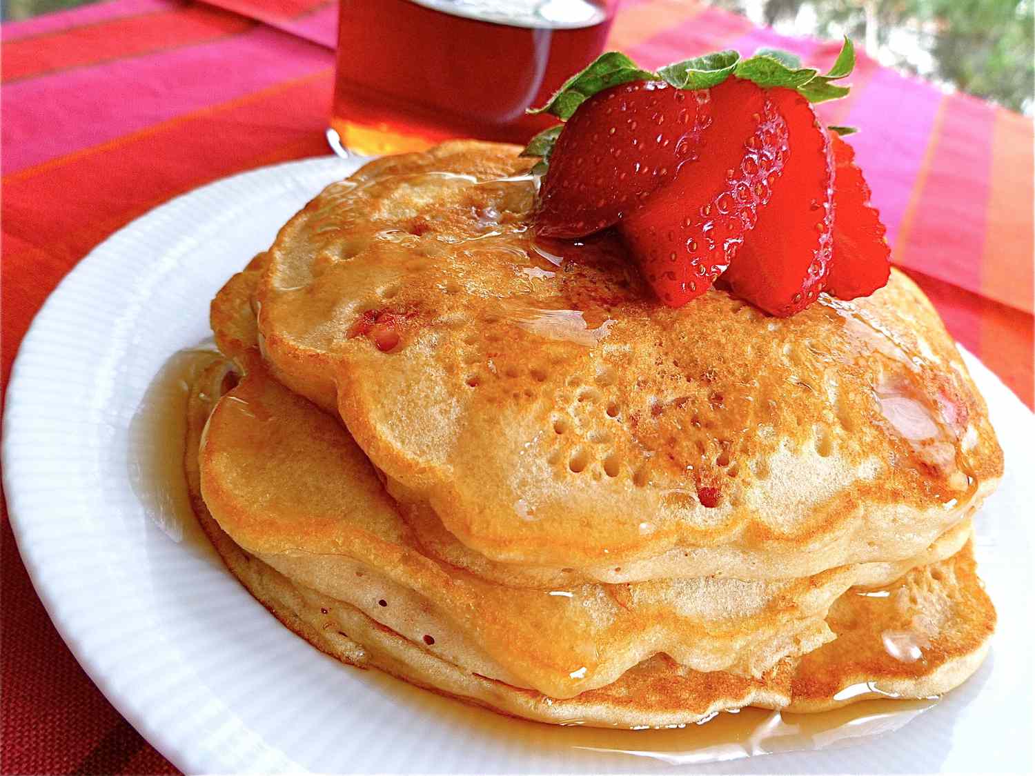 close up view of Strawberry Vanilla Pancakes garnished with a sliced strawberry on a white plate