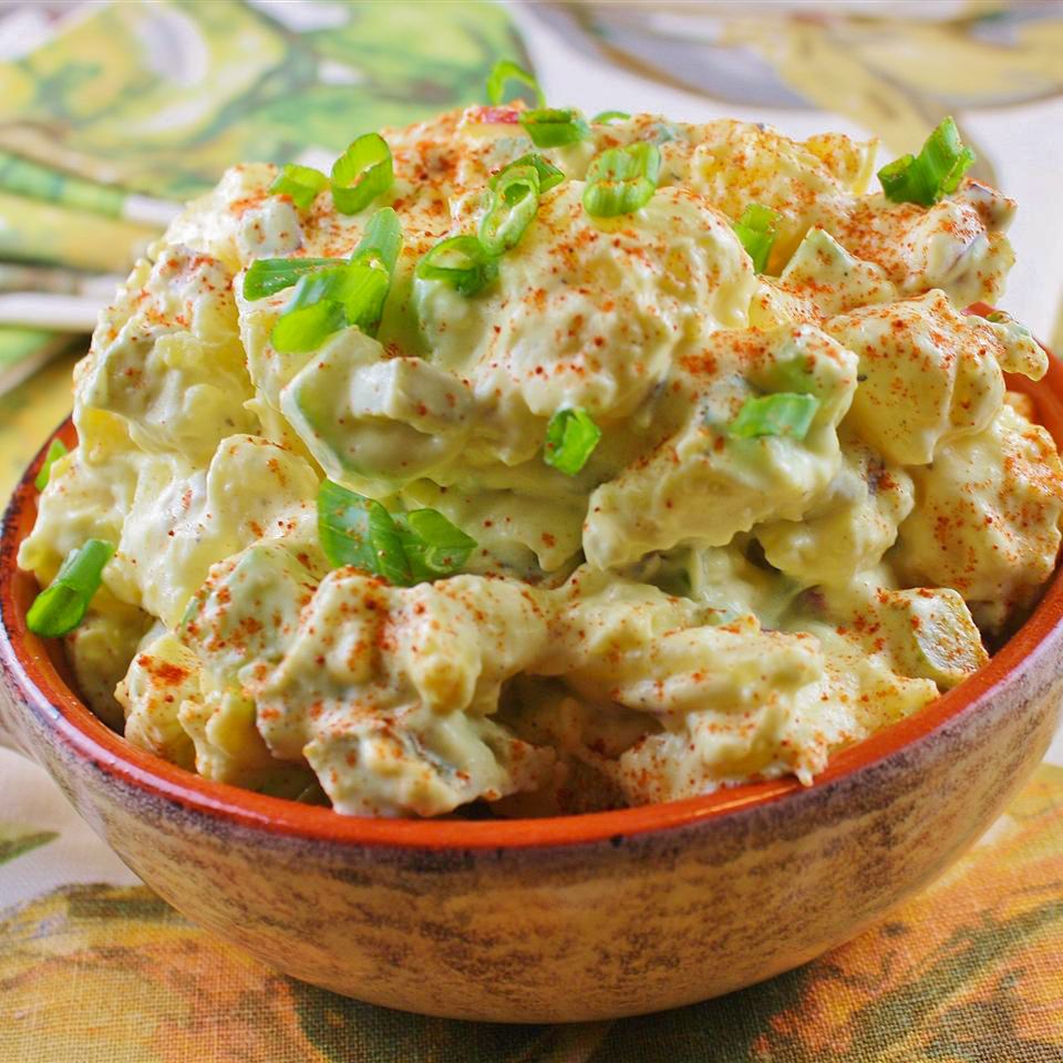 close up view of Potato Salad garnished with green onions in a brown and orange bowl
