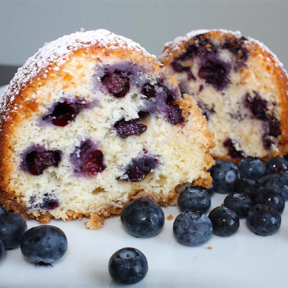 close up view of sliced Blueberry Coffee Cake garnished with powdered sugar and blueberries on a plate