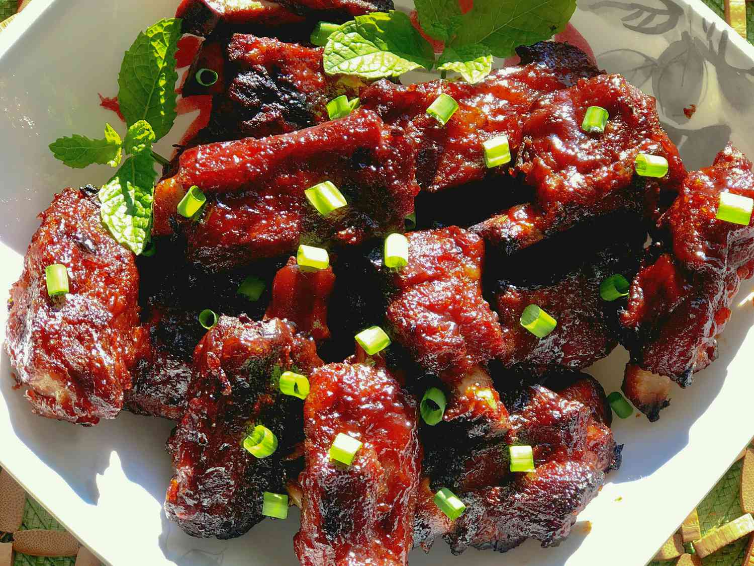 close up view of Pork Rib Tips garnished with green onions and mint leaves in a bowl