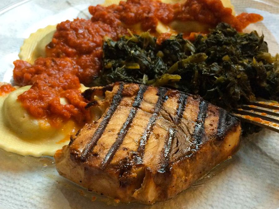 close up view of Grilled Marinated Swordfish served with ravioli with tomato sauce and collard greens