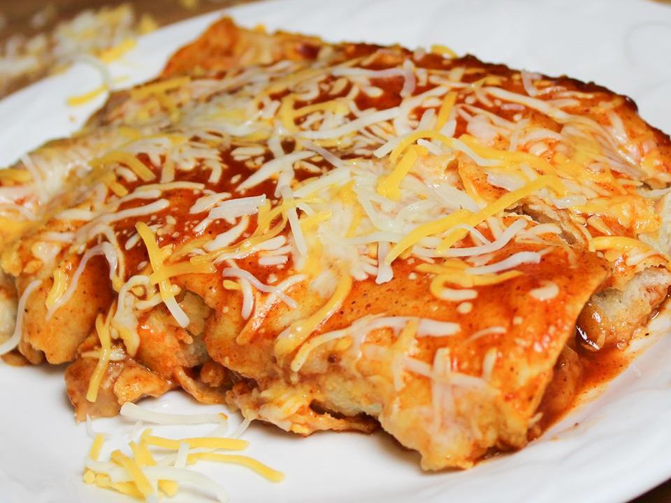 close up view of Refried Bean and Cheese Enchiladas topped with cheese on a platter