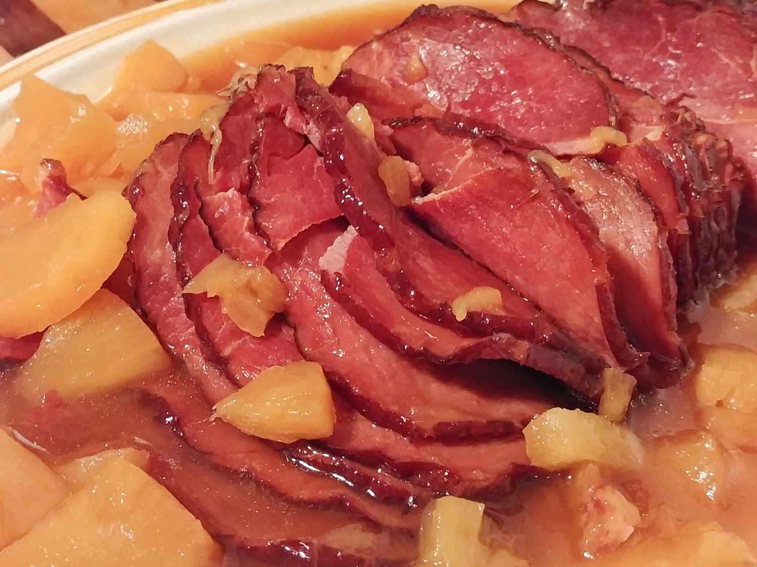 close up view of sliced Instant Pot Ham in a white bowl with pineapple pieces