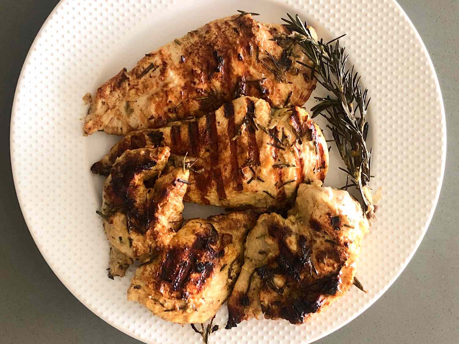 close up view of Grilled Rosemary Chicken Breasts on a white platter