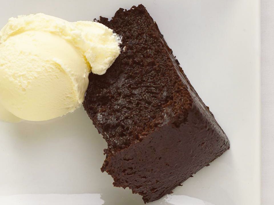 close up view of a slice of Chocolate Cake with a scoop of vanilla ice cream on a white plate
