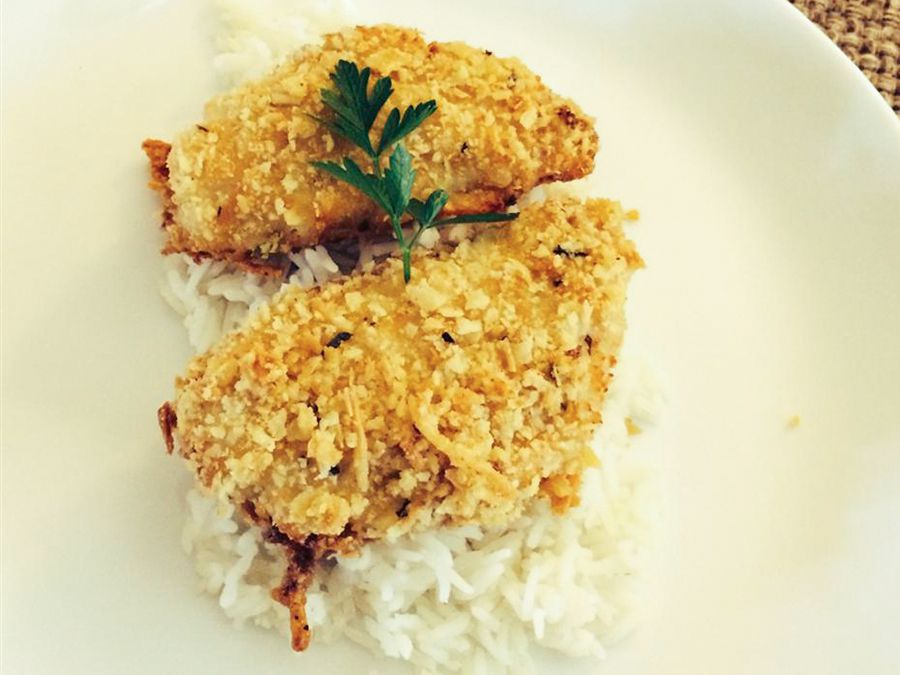 close up view of Baked Butter Herb Perch Fillets over white rice garnished with fresh herbs, on a white plate