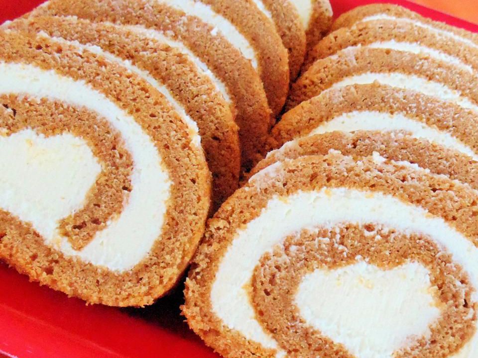 close up view of a sliced Cream Cheese Pumpkin Roll on a red platter