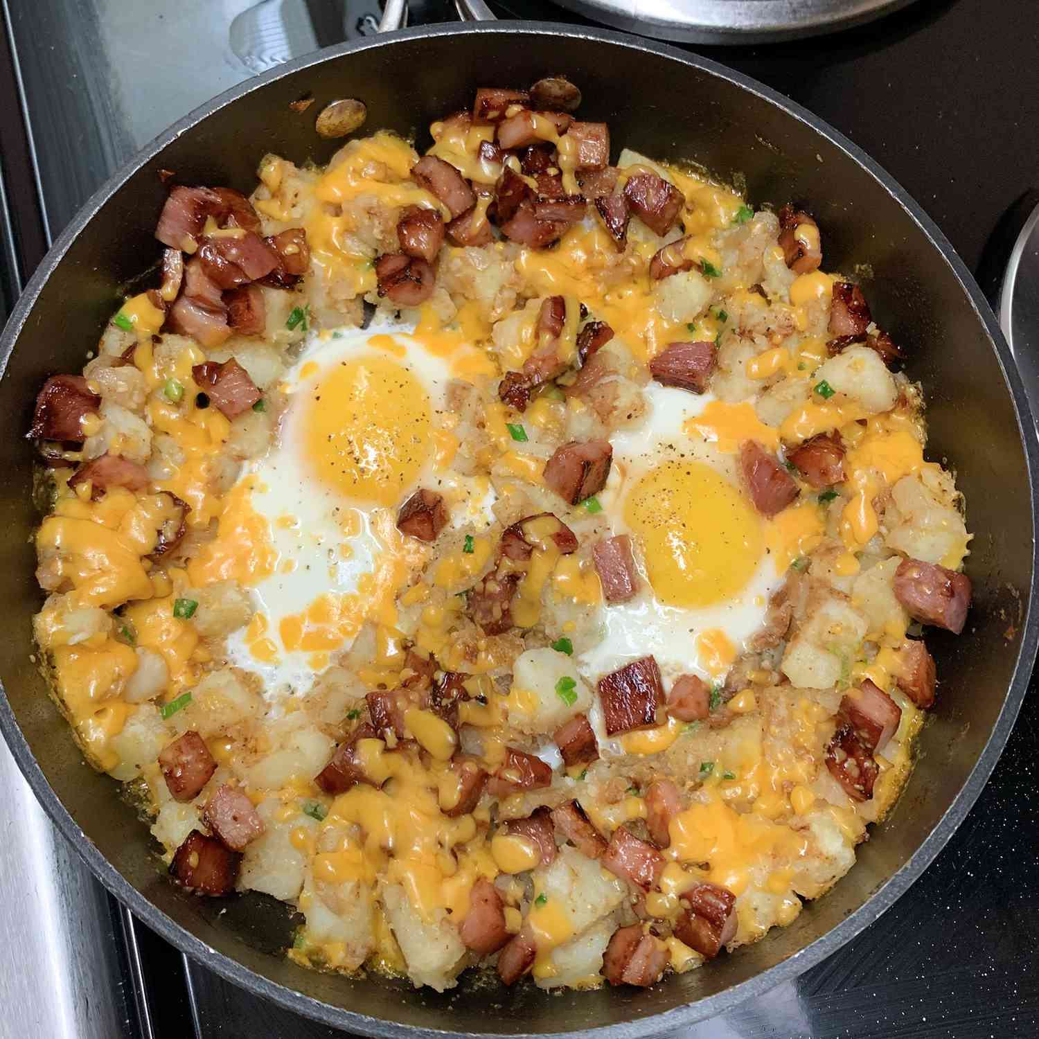 close up view of a Loaded Breakfast Skillet in a cast iron skillet on a stove