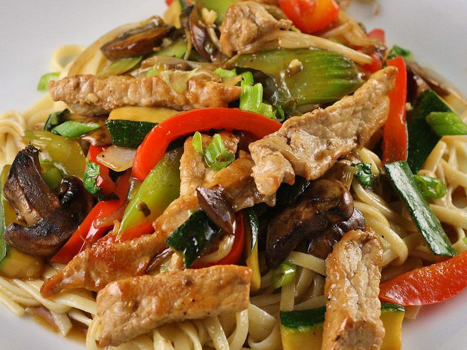 close up view of Stir-Fried Vegetables with Chicken, peppers, mushrooms, zucchini, celery and noodles on a white plate