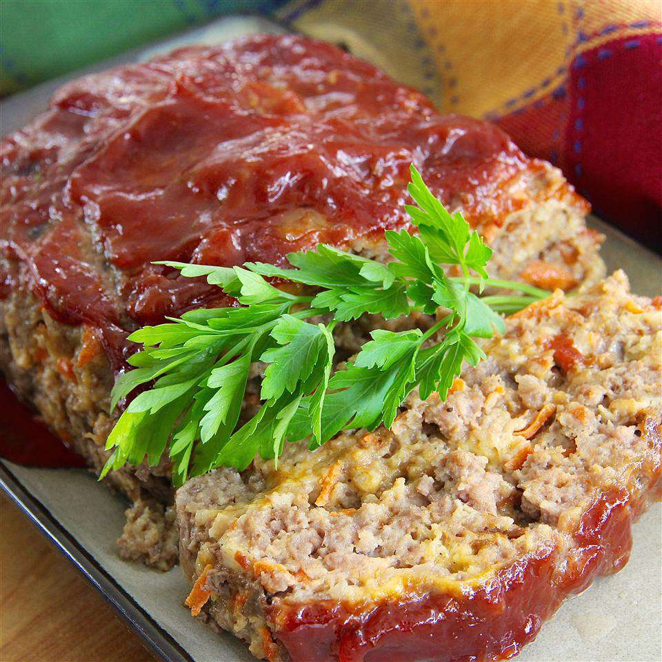 a ketchup- and chili sauce-based glaze shown on top of a meatloaf with a slice in the foreground