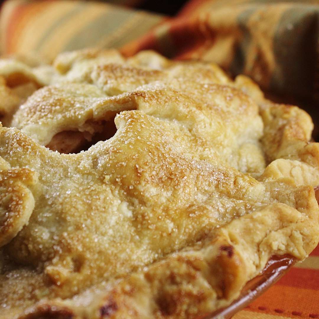 closeup of a two-crust apple pie with apple-shaped cutouts in the pastry