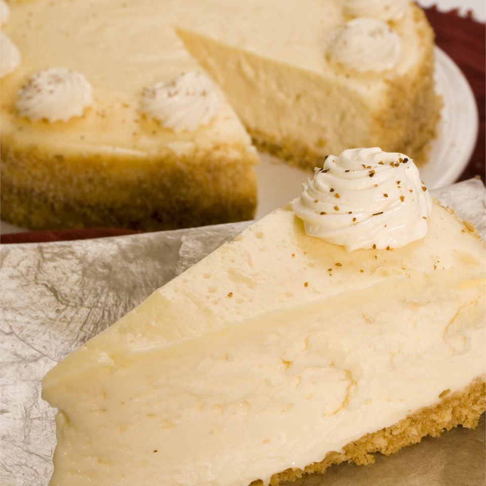 close up view of a slice of Eggnog Cheesecake with Eggnog Cheesecake in the background
