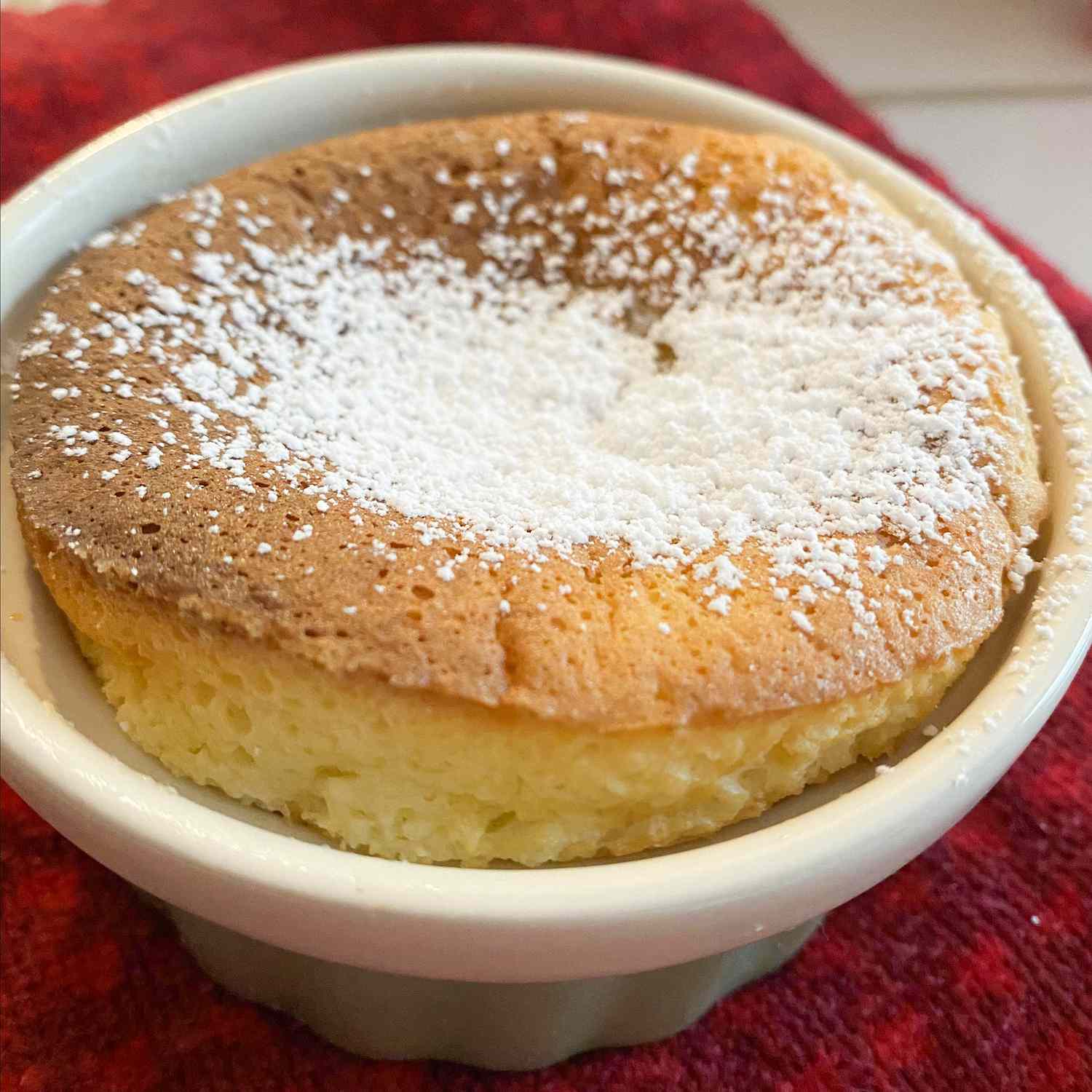 close up view of a Grand Marnier Souffle in a ramekin garnished with powdered sugar