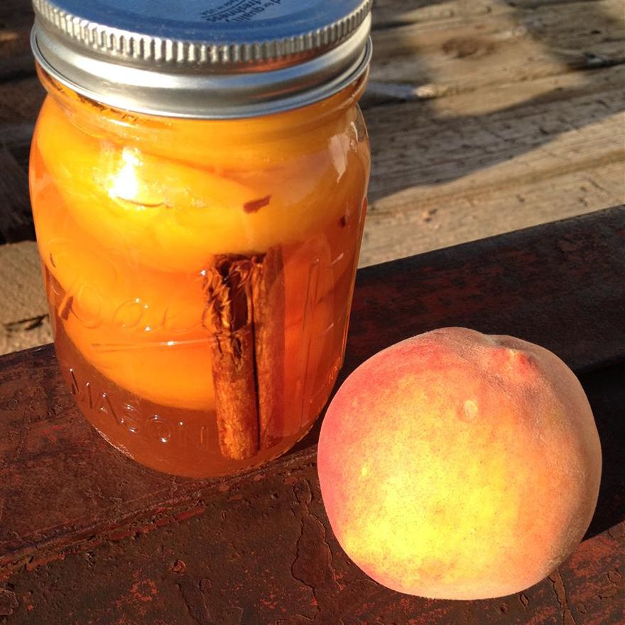 close up view of Pickled Peaches in a jar next to a fresh peach