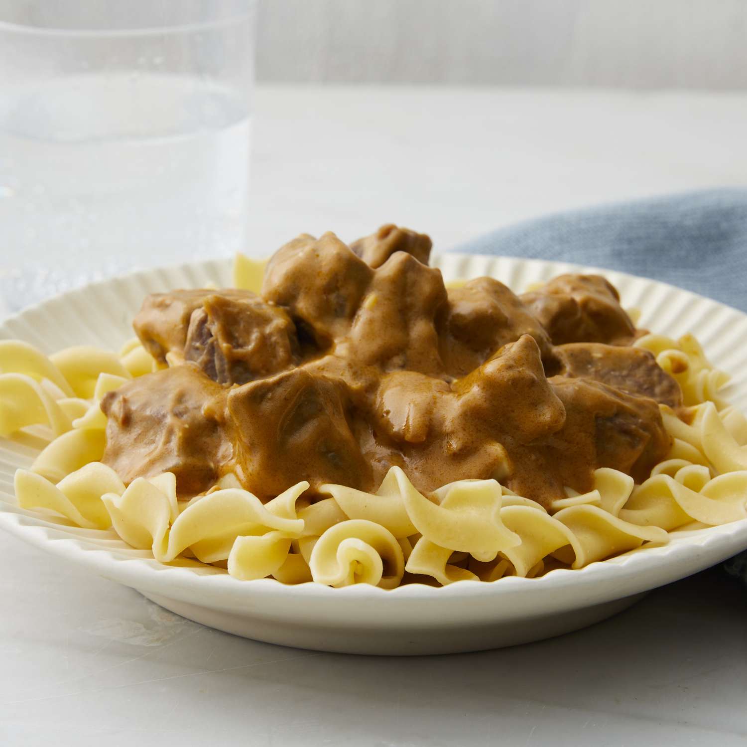 mid angle, looking at a plate of egg noodles topped with beef stroganoff