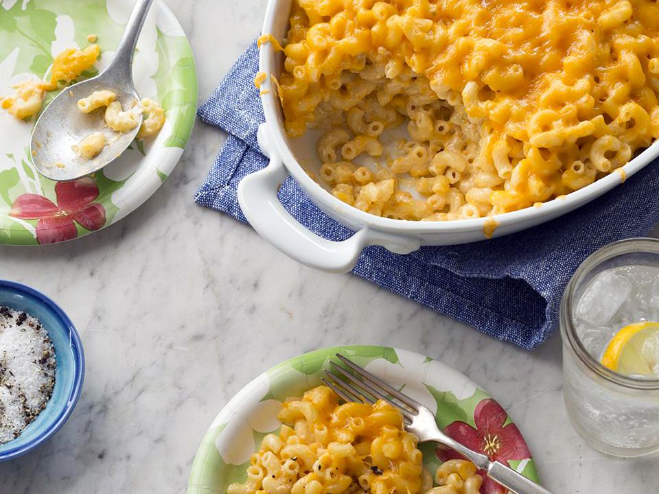 close up view of Baked Mac n Cheese in a glass baking dish, and Mac n Cheese on white plates
