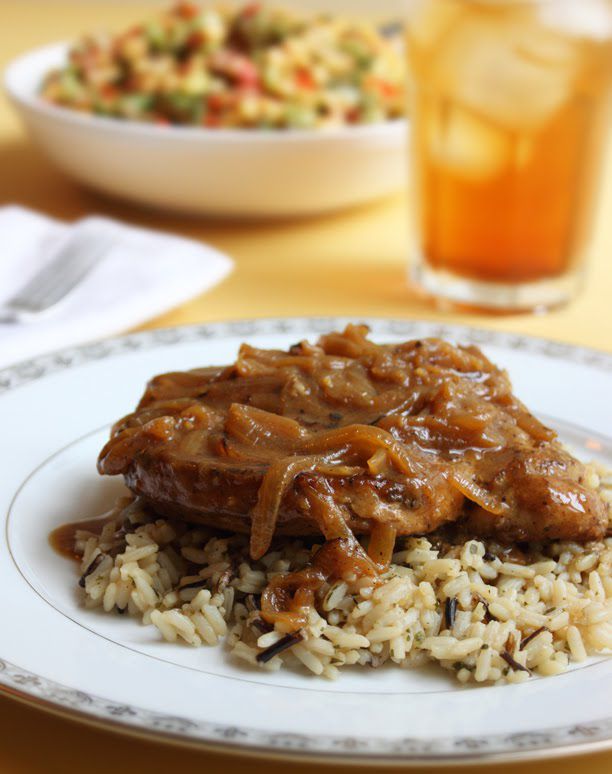 an onion gravy-topped pork chop on a bed of rice