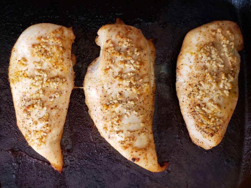 close up view of baked chicken breasts on a baking sheet