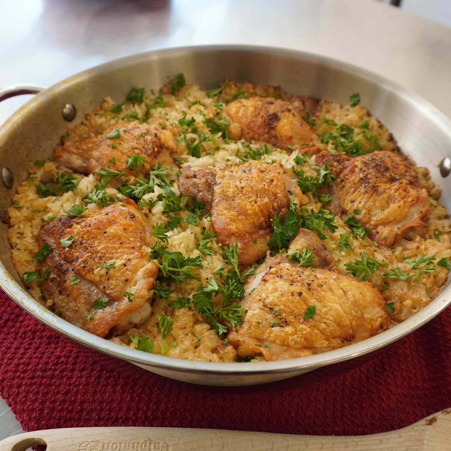 close up view of One-Pot Crispy Chicken and Rice garnished with fresh herbs in a pan