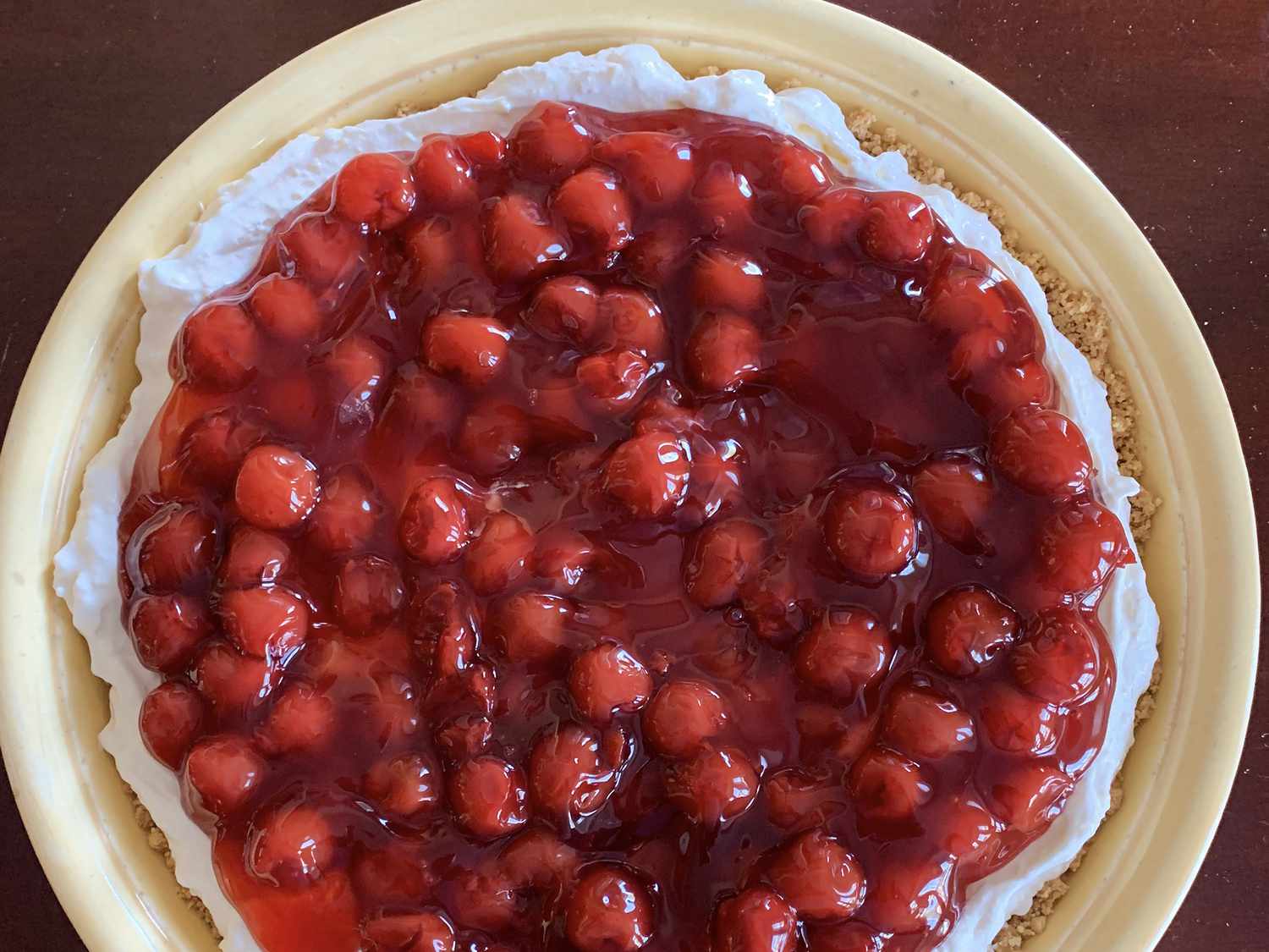 close up view of Opal's Cherry Delight topping over a cheesecake in a pie plate